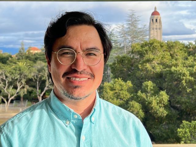 Headshot of Jose Dinenny iwith the skyline of Palo Alto behind him.